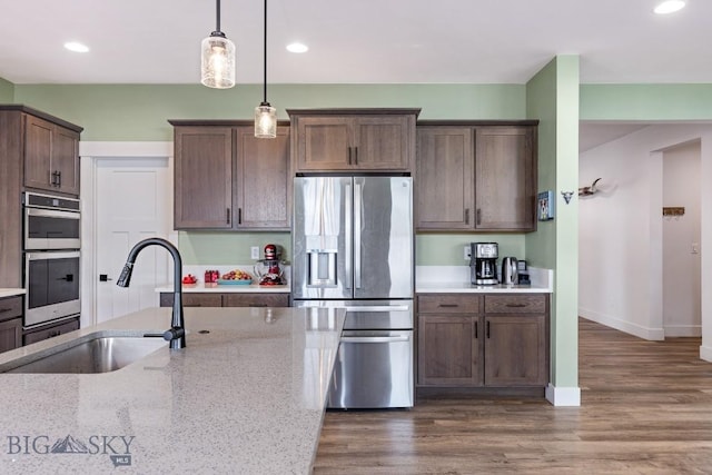 1508 Deadwood Loop, Belgrade, MT 59714 - kitchen featuring appliances with stainless steel finishes, a sink, hanging light fixtures, recessed lighting, and light stone countertops