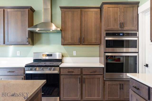 kitchen with light countertops, appliances with stainless steel finishes, and wall chimney exhaust hood
