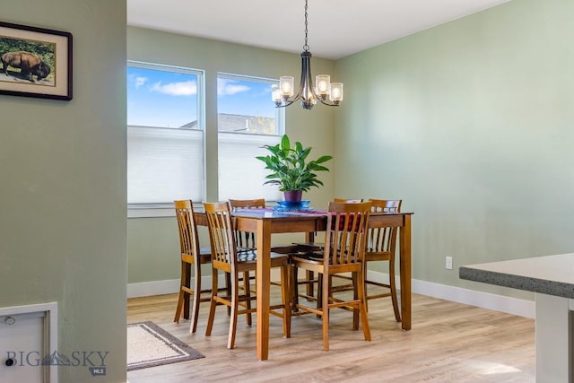 dining room with baseboards, light wood-type flooring, and a chandelier