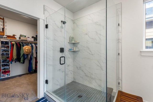 full bathroom with baseboards, a spacious closet, and a shower stall