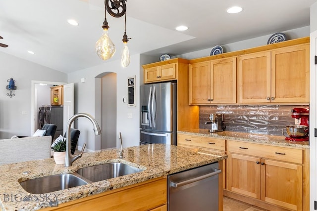 1708 Drummond Blvd, Belgrade, MT 59714 - kitchen featuring appliances with stainless steel finishes, a sink, arched walkways, light stone counters, and lofted ceiling