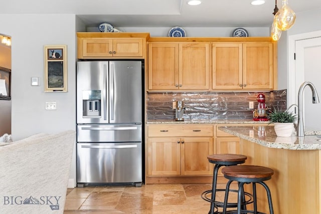 1708 Drummond Blvd, Belgrade, MT 59714 - kitchen with stainless steel refrigerator with ice dispenser, backsplash, light brown cabinets, recessed lighting, and light stone counters