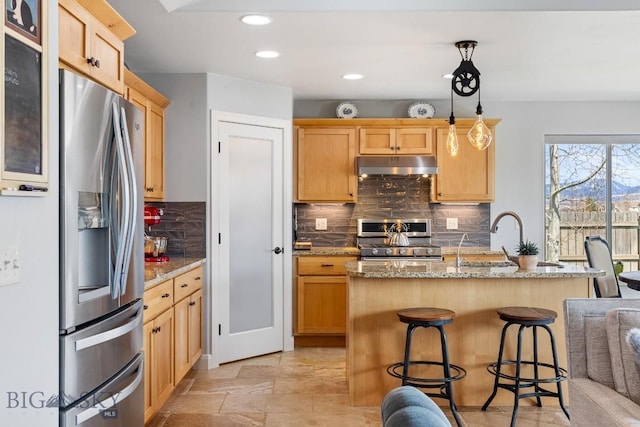 1708 Drummond Blvd, Belgrade, MT 59714 - kitchen featuring appliances with stainless steel finishes, under cabinet range hood, light brown cabinetry, backsplash, and recessed lighting