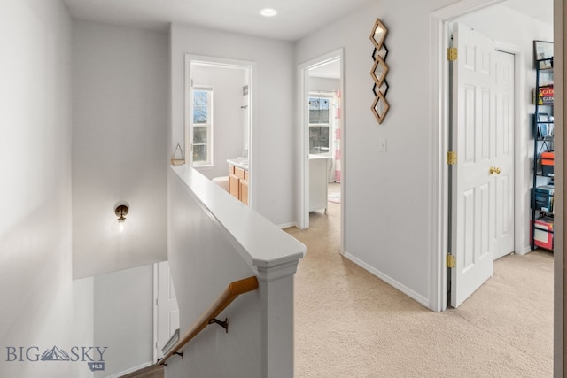 corridor featuring a wealth of natural light, baseboards, and light colored carpet