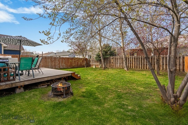 view of yard with a fire pit, a deck, and a fenced backyard