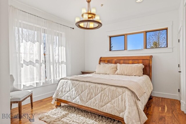 31 Haystack Dr, Bozeman, MT 59718 - bedroom with wood finished floors, baseboards, and an inviting chandelier