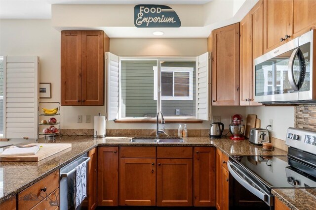 268 Pine Creek Dr, Bozeman, MT 59718 - kitchen featuring dark stone counters, stainless steel appliances, brown cabinets, and a sink