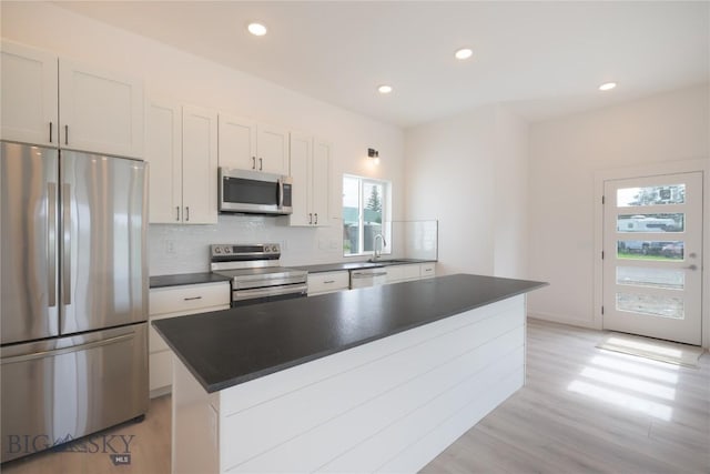 209 Pearl St, Ennis, MT 59729 - kitchen with appliances with stainless steel finishes, dark countertops, decorative backsplash, light wood-style flooring, and recessed lighting