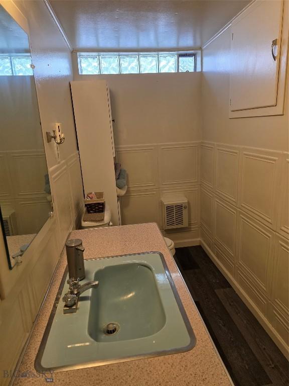 606 S Arizona, Dillon, MT 59725 - half bathroom featuring a sink, a decorative wall, toilet, and wood finished floors