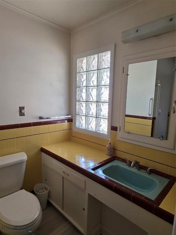 606 S Arizona, Dillon, MT 59725 - bathroom with toilet, ornamental molding, vanity, wood finished floors, and tile walls