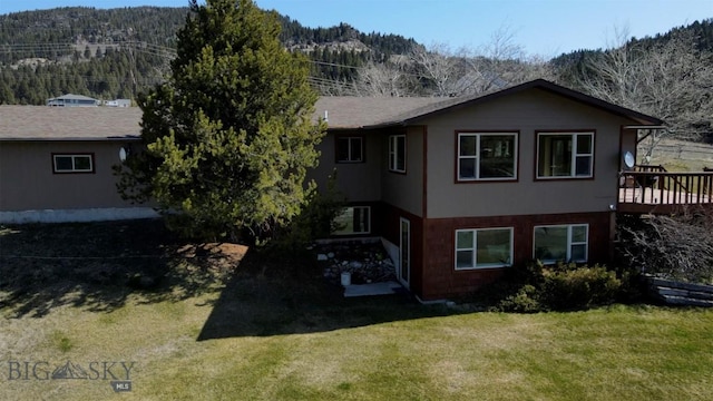 back of house featuring a deck with mountain view and a lawn