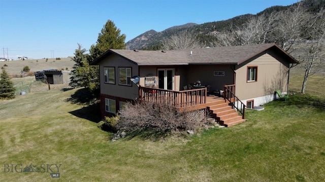 rear view of property featuring a deck with mountain view and a yard