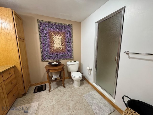 full bathroom featuring baseboards, a shower stall, toilet, and tile patterned flooring