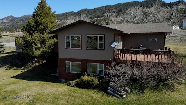 back of property featuring a lawn and a deck with mountain view