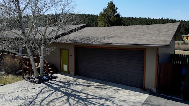 detached garage featuring fence and a view of trees
