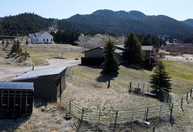 exterior space with a rural view, a pole building, an outbuilding, a mountain view, and fence
