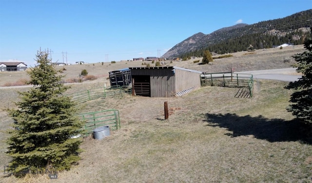 view of yard with a rural view, an outbuilding, a mountain view, fence, and an exterior structure