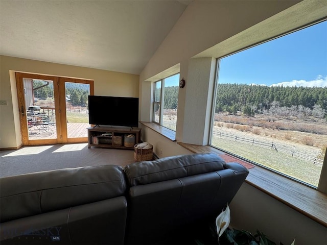 living room with carpet floors, french doors, and vaulted ceiling