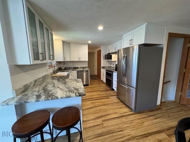 kitchen with white cabinetry, tasteful backsplash, appliances with stainless steel finishes, and light wood-type flooring
