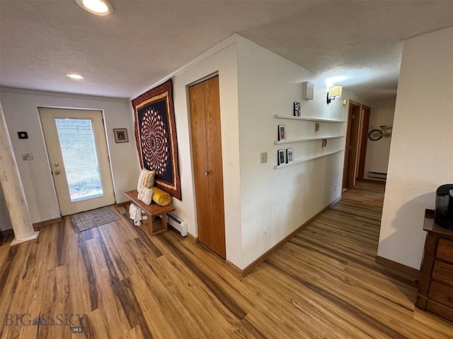 interior space featuring a baseboard radiator, wood finished floors, ornamental molding, and baseboards