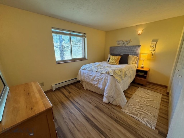 bedroom with baseboards, wood finished floors, and a baseboard radiator