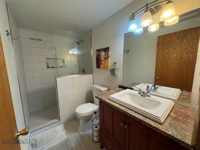 bathroom featuring walk in shower, toilet, a textured wall, vanity, and a textured ceiling