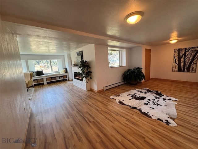 interior space with a glass covered fireplace, wood finished floors, and a baseboard radiator