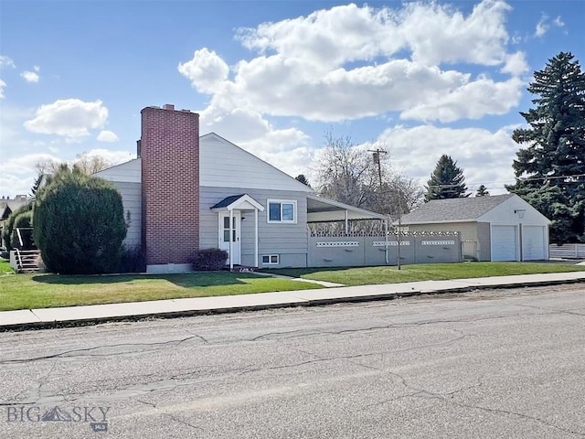 view of front facade with a chimney, fence, a front lawn, and a detached garage
