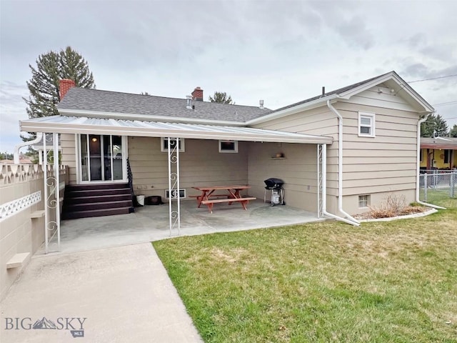 rear view of property featuring entry steps, a chimney, a patio area, a lawn, and fence