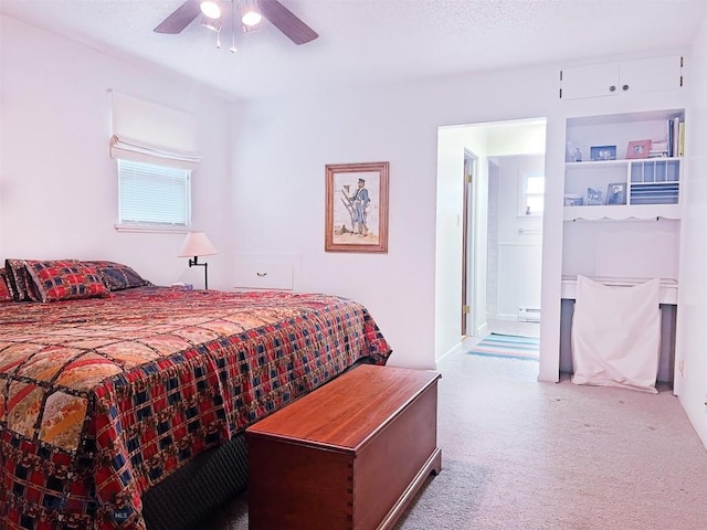 bedroom featuring a baseboard heating unit, ceiling fan, carpet, and ensuite bath