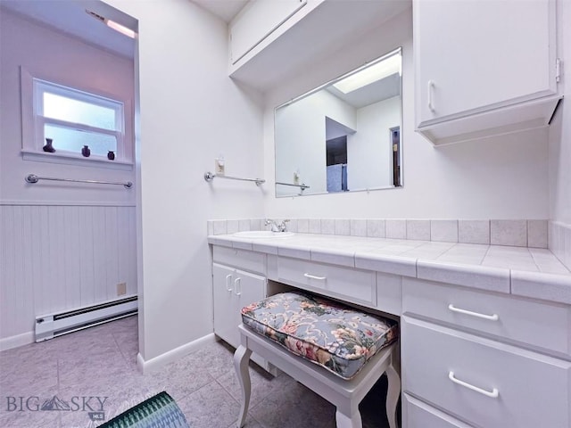 bathroom with baseboard heating, baseboards, tile patterned flooring, and vanity