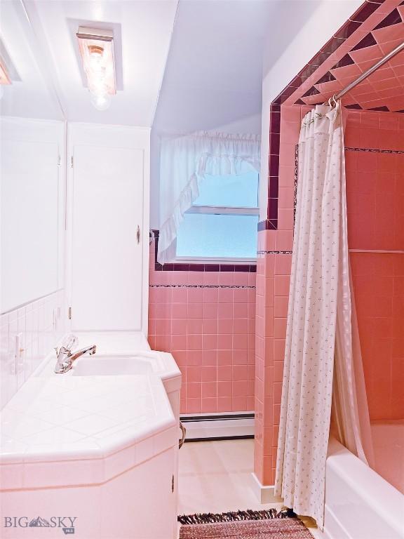 full bath with shower / bath combination with curtain, tile walls, vanity, and a baseboard radiator