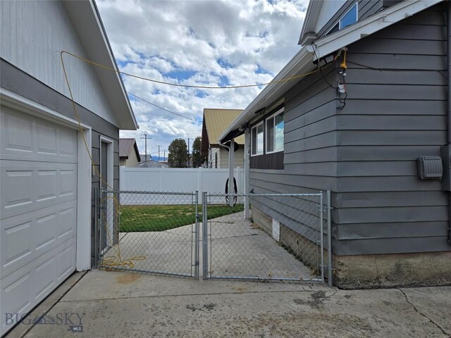 view of property exterior featuring fence, a garage, and a gate