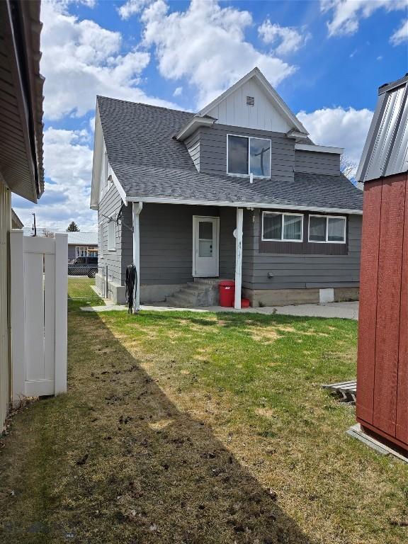 back of property with roof with shingles, a yard, and board and batten siding