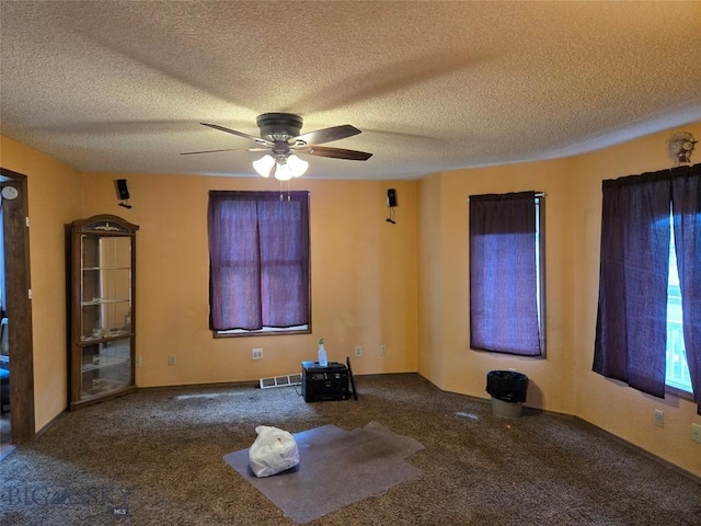 unfurnished room featuring a textured ceiling, visible vents, a ceiling fan, and carpet flooring