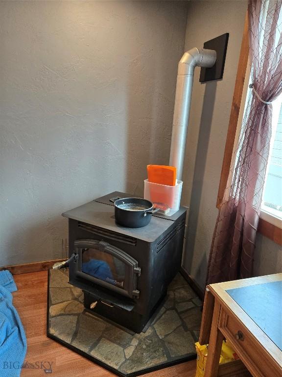room details with wood finished floors, a textured wall, a wood stove, and baseboards