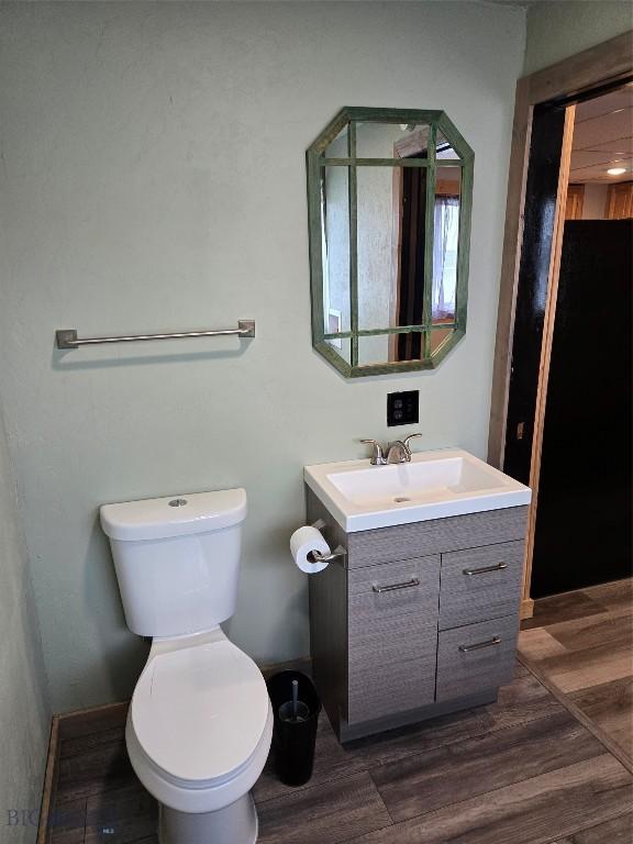 bathroom with toilet, wood finished floors, vanity, and baseboards