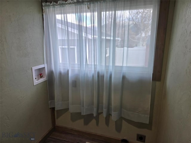 empty room featuring baseboards, wood finished floors, and a textured wall