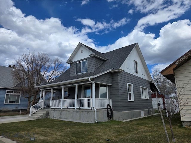 bungalow-style home with covered porch, board and batten siding, a front lawn, and roof with shingles