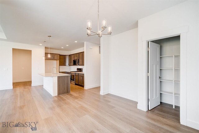 1520 Cyril Way, Belgrade, MT 59714 - kitchen with appliances with stainless steel finishes, light countertops, light wood-style floors, hanging light fixtures, and a chandelier