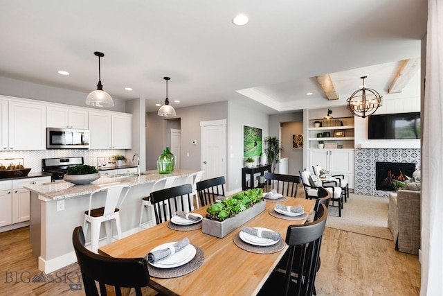 1202 Cody Way, Belgrade, MT 59714 - dining space featuring light wood finished floors, recessed lighting, a notable chandelier, and a fireplace