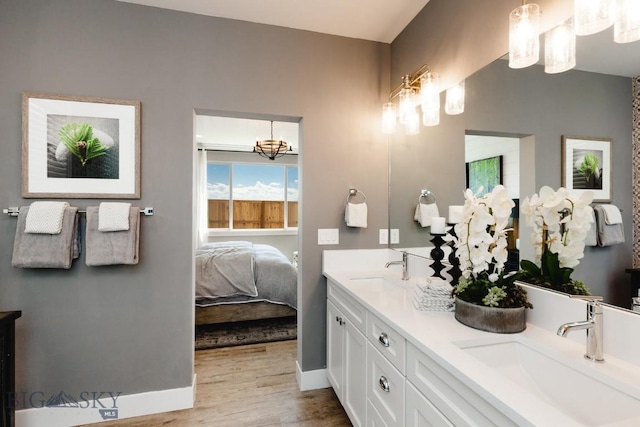 1202 Cody Way, Belgrade, MT 59714 - ensuite bathroom with a notable chandelier, double vanity, a sink, and wood finished floors