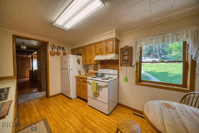 14470 Cottonwood Canyon Rd, Bozeman, MT 59718 - kitchen with brown cabinetry, white appliances, visible vents, under cabinet range hood, and light wood-style floors