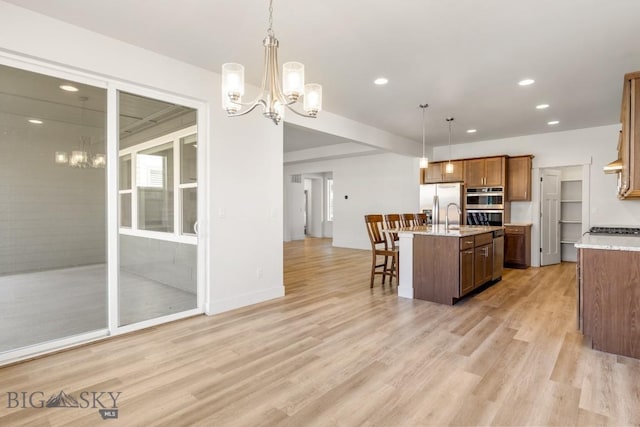 1511 Masterson, Belgrade, MT 59714 - kitchen with light wood-style flooring, a breakfast bar, appliances with stainless steel finishes, and a chandelier