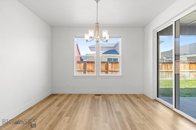 1511 Masterson, Belgrade, MT 59714 - unfurnished dining area featuring a notable chandelier, baseboards, and light wood-type flooring