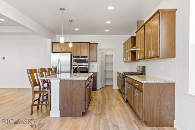 1511 Masterson, Belgrade, MT 59714 - kitchen featuring a breakfast bar, stainless steel appliances, light wood finished floors, and a sink