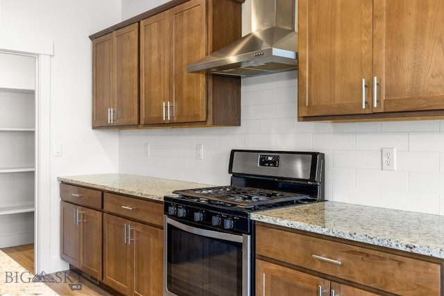 1511 Masterson, Belgrade, MT 59714 - kitchen featuring wall chimney exhaust hood, light stone counters, decorative backsplash, and stainless steel range with gas cooktop
