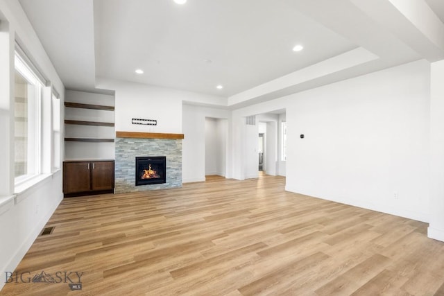 1511 Masterson, Belgrade, MT 59714 - unfurnished living room featuring visible vents, light wood-type flooring, a warm lit fireplace, and recessed lighting