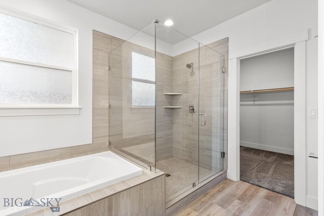 1511 Masterson, Belgrade, MT 59714 - bathroom featuring a walk in closet, a stall shower, a garden tub, and wood finished floors