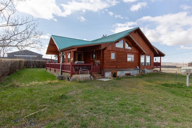 back of house featuring log siding, metal roof, a lawn, board and batten siding, and fence